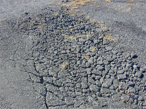 Photo showing a small area of high-severity alligator cracking where the cracks are well defined and spalled, and many of the small pieces between the cracks appear loose (i.e., a FOD potential).