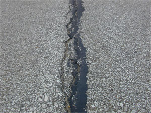 Close-up photo of a single high-severity crack. The crack is sealed, but very wide (i.e., greater than 1 in (25 mm)).