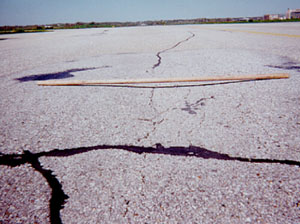 Overview photo of a pavement with a visible area of high-severity rutting. A 6-foot (2-meter) long piece of wood has been placed across the rut to show the depth of the rut.