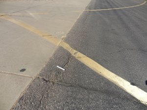 Overview photo showing a longitudinal joint between a PCC and an asphalt pavement. The photo shows a slight amount of shoving of the asphalt for a short distance along the joint.
