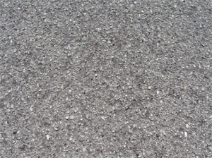 Close-up photo of a small area of asphalt pavement surface with a noticeable loss of coarse aggregate. The surface is noticeably pitted.