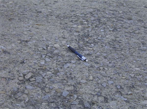 Close-up photo of the pavement surface showing a more significant area of scaling. In this photo, the majority of the visible pavement surface looks very pitted.