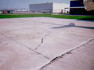 Overview photo showing a slab that is broken into four or five larger pieces. The cracks that divide the pieces are medium-severity cracks.