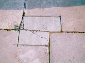 Overview photo of two small PCC patches on either side of a transverse joint. Both patches show cracking within the patched area.