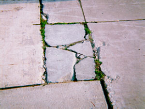 Close-up of a rectangular PCC patch that is divided into more than five pieces. The cracks that divide the patch into the different pieces are very wide high-severity cracks.