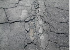 This picture shows a closeup of an asphalt pavement with high-severity (i.e., deteriorated) cracking.  The PCI of the pavement in the image is 5.